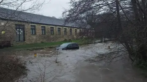 A car trapped in some flood water outside a building in Brighouse, West Yorkshire