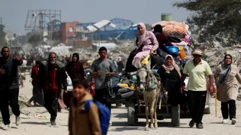 Reuters Gazans walking in a street carrying their belongings, along with a car led by a donkey 