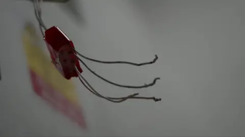 The picture shows a close-up of some broken wiring, exposed in the flats.