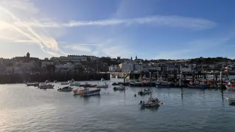BBC Picture of St Peter Port with fishing boats on the water in the foregorund and the townscape behind