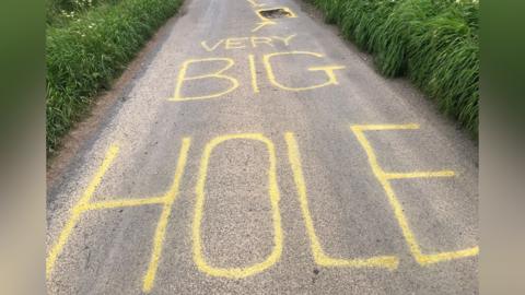 "Very big hole" painted on a road