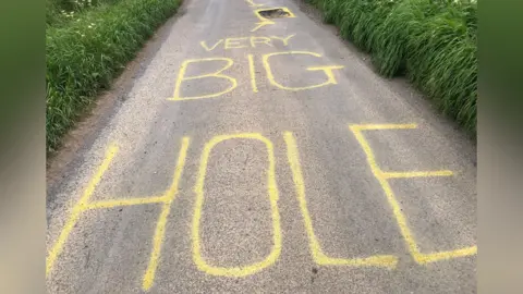 John Devine/BBC "Very big hole" painted on a road