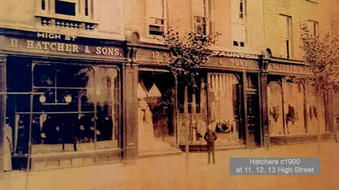 Hatchers An old photograph from 1900 of the Hatchers store. It is a sepia photograph and shows a man standing outside the shop.