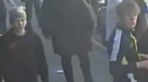 Sussex Police Two young males captured on blurry CCTV image walking down a street.