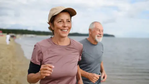Two people running along the beach