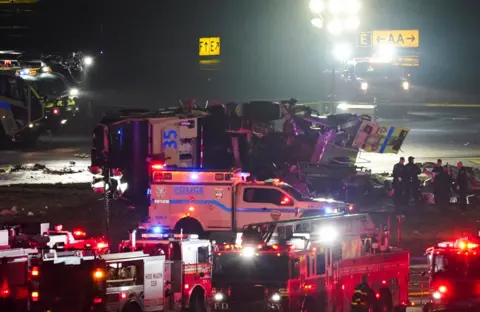 Emergency vehicles with their lights flashing at the scene of the crash at La Guardia airport