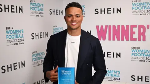 Getty Images Jermaine Jenas uśmiecha się i trzyma nagrodę podczas rozdania nagród Women's Football Awards