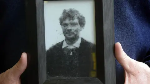 Hands holding a framed picture of John Patrick Cunningham.