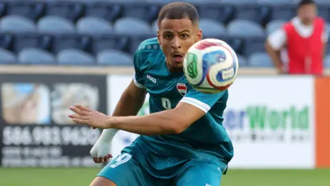 Ali Al-Hamadi, who has a shaved head, has his eye on the ball in his Iraqi strip during a friendly played before the World Cup in the USA.