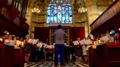Dima Dmytro composing a choir in a church.