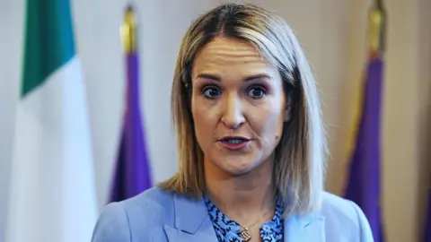 PA Media Irish Foreign Affairs Minister Helen McEntee, with shoulder length blond hair, wearing a blue shirt and a blue jacket. 