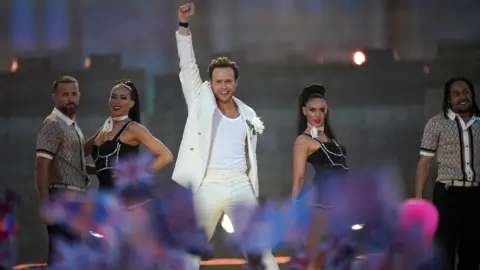 Yui Mok/PA Media Olly Murs performing on stage with his fist in the air alongside four dancers