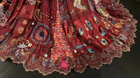 The hem of the dress is highly decorative with sequined lace and multicoloured embroidery. 