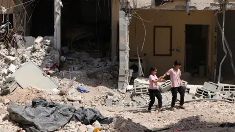 Alaa Badarneh Palestinian girls walk on the rubble of damaged buildings and tarmac in Nur Shams refugee camp, in the occupied West Bank, after a two-day Israeli military operation (30 August 2024)