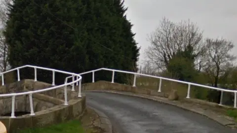 The road bridge curving to the right with white railings on either side