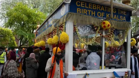 City of Wolverhampton Council A large decorated float with glass windows, surrounded by a large crowd of people