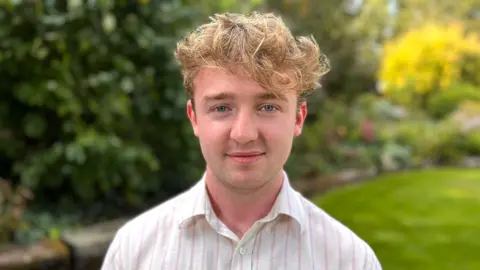  Martin Giles/BBC Isaac smiling into the camera outside.