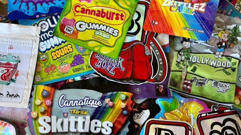 A collection of colourful packets designed to look like sweet packets bearing names such as Cannaburst Gummies and Cannatique Skittles