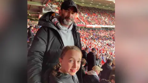Sarah Rimmer Mr Rimmer and his daughter Amelia at football stadium - crowds in background wear red.