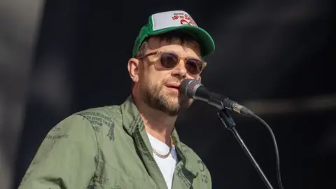 Getty Images Damon Albarn pictured in a cap and sunglasses while performing on-stage at Glastonbury Festival in 2024