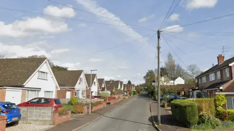 Carterford Drive in Norwich is pictured. The residential road is lined either side with houses. Cars can be seen parked in driveways.