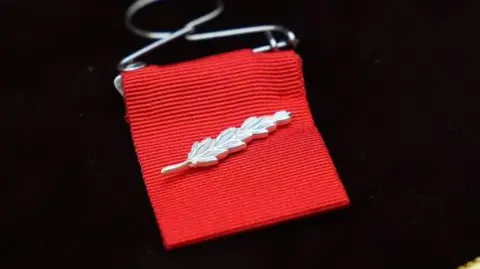 Getty Images The King's Commendation for Bravery by King Charles III, a silver pin in the shape of an ear of grain.