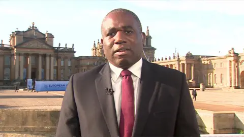 BBC David Lammy wearing a suit and red tie as a speaks to camera during an interview with the BBC live from Blenheim Palace