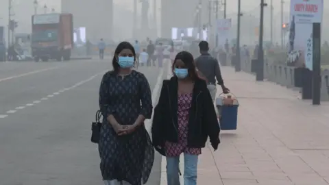 EPA/Shutterstock Indian girls wearing face masks walk amid heavy smog at Rajpath in New Delhi, India on 31 October, 2025. 