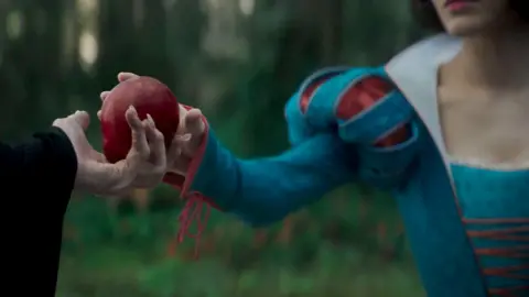 Disney One of the most famous Snow White moments is when she takes a magic blood-red apple from the Evil Queen, we see their hands exchanging the apple