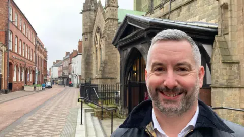 A man smiling on the street outside the cathedral