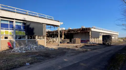 Part of former Delphi factory has been removed, leaving two stand alone buildings, rubble and twisted metal can be seen on the floor.