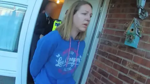 Police bodycam footage of Lucy Letby, wearing a blue hoodie, being led from her front door in handcuffs