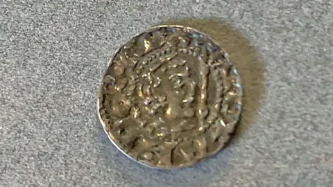 An old coin in close-up with the outline of possibly a silvery face on its surface