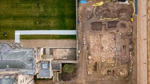 Alexander Jansen/Durham University An aerial shot of the ruins. The land is dug and there are stones strewn across the site. There is a grass field to the left.