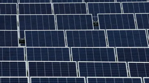 A stock image of solar panels in a solar farm