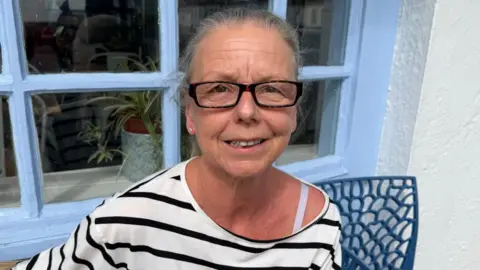 Tracey Benn is pictured outside Cafe Louise in Gorey. She is wearing a white top with black stripes. She is also wearing glasses.