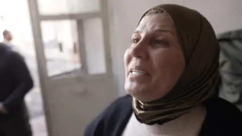 A woman wearing a brown scarf crying. 