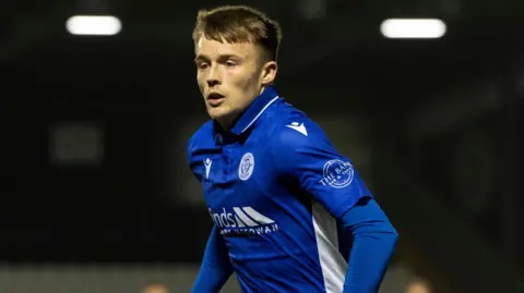 Lewis Gibson a young, blond haired footballer in a Queen of the South strip - a blue shirt