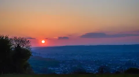 Getty Images A red sun rises above many homes