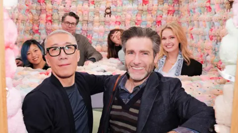 Pop Mart Labubu creator Kasing Lung (left) and director Paul King pose for pictures at a Pop Mart exhibition in Paris, surrounded by hundreds of Labubu dolls.