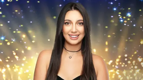 Eurovision/Tal Givoni Seorang wanita digambarkan tersenyum dengan kilauan cahaya terang di belakangnya.