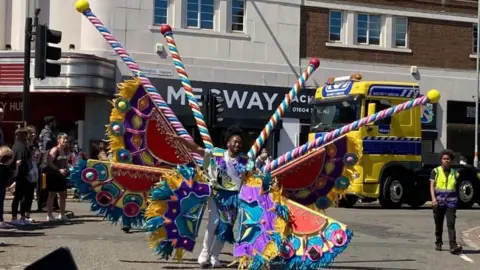 A man in a colourful costume in a carnival parade