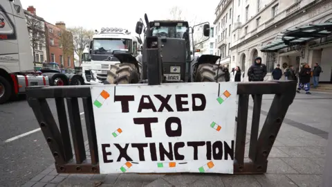 A sign that says taxed to extinction on the front of a tractor 