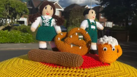 Yarnbombing Stapleford Two woman in traditional outfits and a pretzel. 