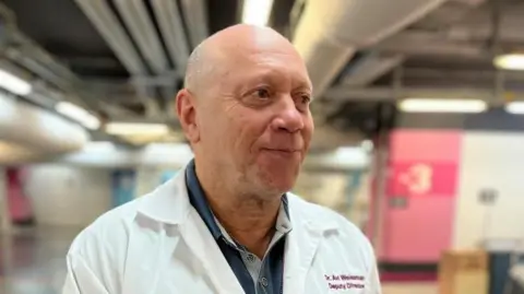 Avi Weissman wears a white medical jacket while being interviewed