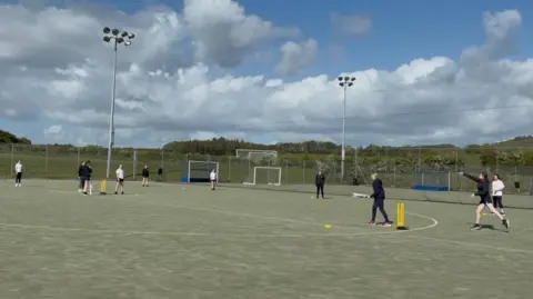 Girls playing softball cricket on an astro turf pitch at Cockermouth School.