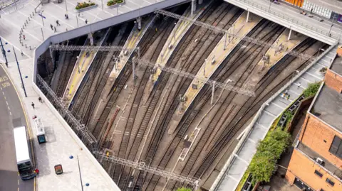 A view from above train tracks and the surrounding streets and pavements in Birmingham as the tracks separate in their approach to New Street Station.
