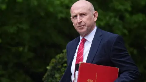 PA Media John Healey carries a red folder