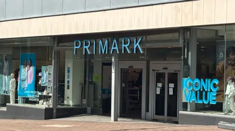 The outside of a Primark store in Stoke-on-Trent, with the word Primark in light blue capital letters above doors.