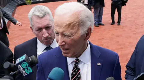 Former US President Joe Biden speaks to reporters, after a ceremony, at Veterans Memorial Park.